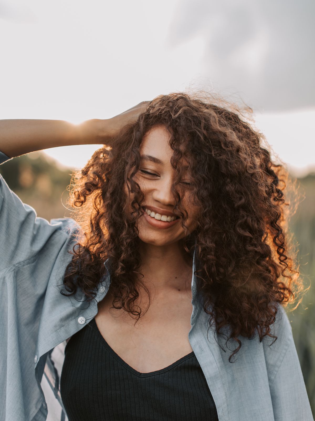 A person smiling outdoors in warm evening light