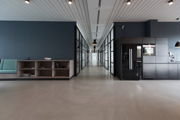 A spacious modern interior with polished floors, a soft seating nook, and a long light-filled corridor