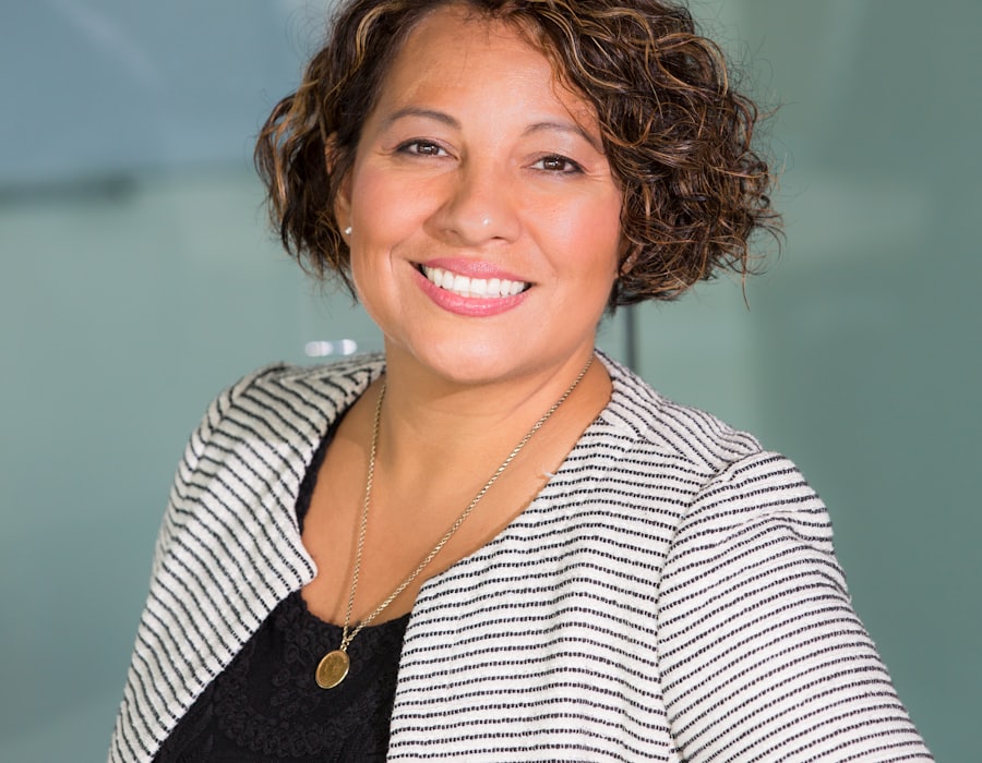 Smiling woman with short curly hair in a striped jacket, warm and welcoming against a soft background
